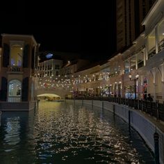 a canal in the middle of a city at night with buildings and lights on either side