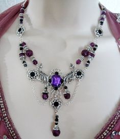 "This beautiful necklace has black glass beads, pewter silver accent beads, purple faceted beads, pewter silver bead caps, seed beads, silver plated bead caps, pewter silver rhinestone accents, metal chain, silver plated filigree pendant with purple faceted glass setting and rhinestones. It can be worn as a choker or adjusted up to 20\" long. Lobster clasp." Gothic Purple Metal Jewelry, Elegant Purple Jewelry With Silver Beads, Gothic Purple Jewelry For Formal Occasions, Ornate Handmade Purple Jewelry, Purple Gothic Jewelry For Formal Occasions, Gothic Silver Beaded Jewelry, Gothic Silver Jewelry With Round Beads, Silver Gothic Beaded Jewelry, Silver Gothic Jewelry With Round Beads