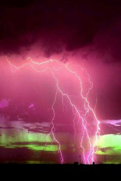 a purple and green sky with lightning in the background