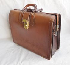 This vintage briefcase is solid and sturdy. Very well made. The tag inside states - Wear Best since 1917 Top Grain Cowhide. I would guess this is from the 1950s or 1960s. Brass locking hardware, no key tho. The front and back are a caramel color leather, the sides and bottom are a chocolate brown leather. There is some normal wear but no damage. Stitching is intact. I like that is had two handles. 13 in tall with 3 1/2 in handles 18 1/4 in wide 6 in wide Check out my handmade clothing at kissmya