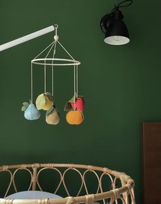 a baby crib with three stuffed animals hanging from it's hooks, and a green wall in the background