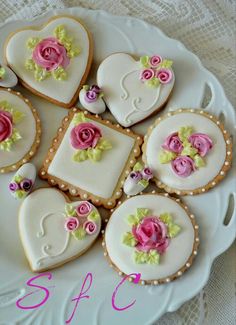 decorated cookies on a white plate with pink and green flowers in the middle, sitting on a lace tablecloth