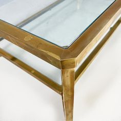 a glass top coffee table with gold metal legs and an acrylic finish on the bottom