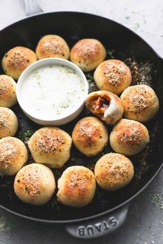 a skillet filled with small rolls and dip in the middle, sitting on a table