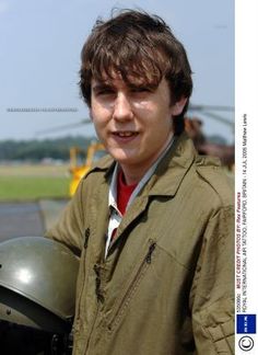 a young man wearing a helmet standing in front of an airplane