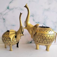 two brass elephants are standing next to each other in front of a white marble wall