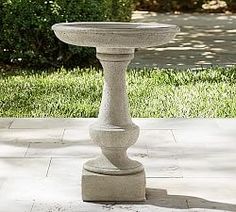 a cement bird bath sitting on top of a sidewalk