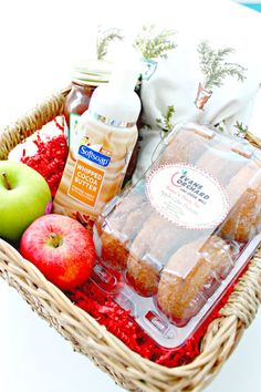 a basket filled with donuts, apples and condiments on top of a table