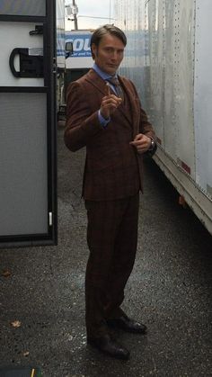 a man in a suit standing next to a truck