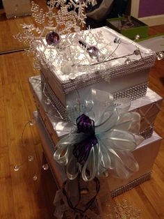 three white boxes stacked on top of each other with ribbons and snowflakes attached to them