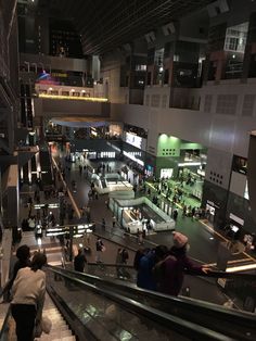 people are walking up and down an escalator in a shopping mall at night