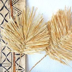 two pieces of straw sitting next to each other on top of a rug in front of a wall