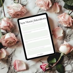 a tablet sitting on top of a marble table next to pink roses