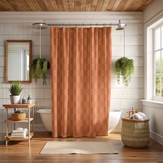 an orange shower curtain in a bathroom next to a toilet and sink with potted plants on the window sill