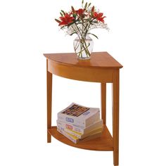 a vase with flowers on top of a wooden table next to books and magazines stacked on it