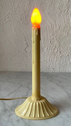 a yellow candle is lit on a marble surface