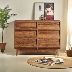 a wooden dresser sitting in a living room next to a potted plant on top of a rug