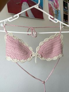 a pink and white bra hanging from a clothes line with pictures on the wall behind it