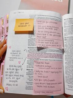 a person holding up a book with sticky notes on it and a piece of paper pinned to the page