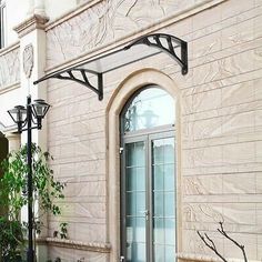 an outdoor area with potted plants and lampposts in front of a building