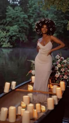 a woman in a white dress standing on a boat with candles