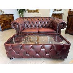 a brown leather couch sitting on top of a table next to a glass coffee table