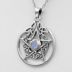 a silver pendant with a white stone in the center and an intricate design on it