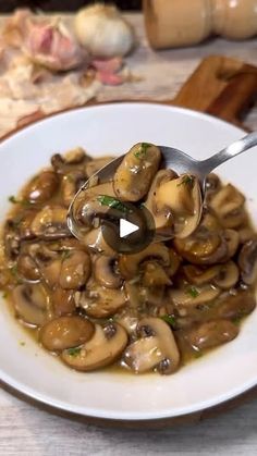 a white plate topped with mushrooms covered in gravy next to a wooden cutting board