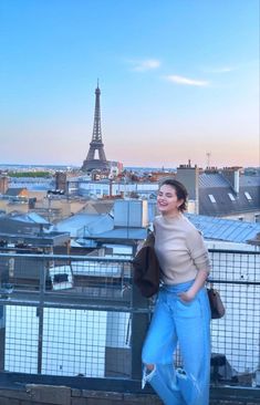 a woman standing on top of a building next to the eiffel tower