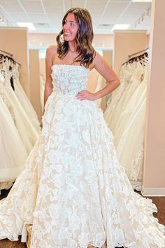 a woman is standing in front of some wedding dresses