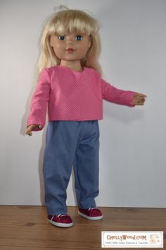 a doll with blonde hair wearing blue pants and a pink top is standing on a wooden floor