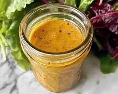 a jar filled with mustard sitting next to a pile of lettuce