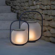 two lamps sitting next to each other in front of a stone wall with steps leading up to it