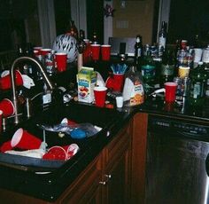 a kitchen sink filled with lots of clutter and empty cups on the counter top