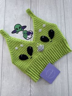 a green knitted hat with alien patches on it