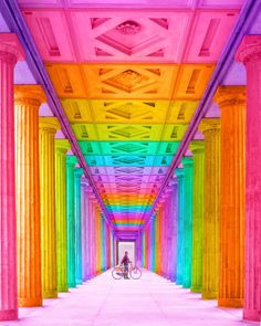 a person with a bike standing in front of an array of colored columns and pillars