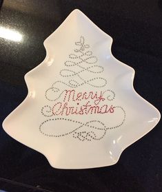 a christmas tree shaped dish with the words merry christmas written in red and silver on it