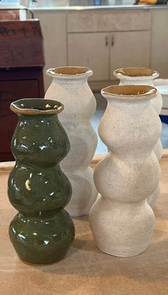 three white and green vases sitting on top of a counter