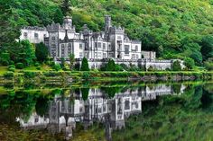 an old castle sitting on top of a lush green hillside next to a body of water