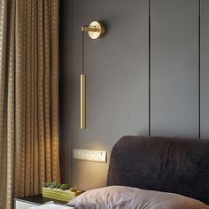 a bed sitting next to a window with curtains on top of it and a lamp hanging from the wall