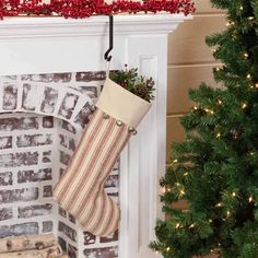 a christmas stocking is hanging on the mantle next to a fire place and tree