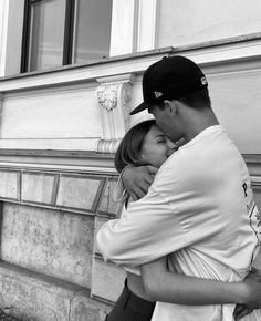 a man and woman embracing each other in front of a building