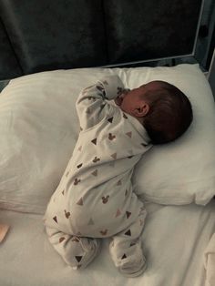 a baby laying on top of a white bed