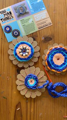 there are crochet flowers and yarns on the wooden table next to each other