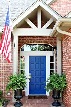 a blue front door with two planters and an american flag