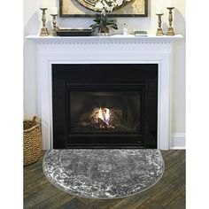 a white fireplace with a painting on the mantle and a rug in front of it