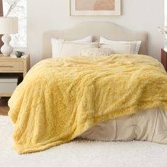 a bed with a yellow blanket on top of it in a bedroom next to two nightstands