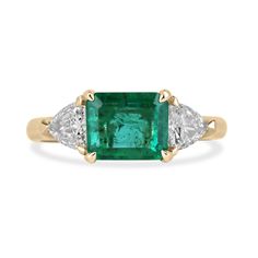 Elevate your style with this exquisite emerald and diamond three-stone ring. The center stage is adorned by a captivating 1.92-carat emerald, showcasing a lush dark green color and very good clarity and luster. Set in a four-claw prong mounting, the emerald is positioned east to west, creating a unique and eye-catching design. Completing the ring are sparkling trillion-cut diamonds accenting the sides, adding a touch of elegance and brilliance. Crafted in a 14k yellow gold setting, this ring is a true statement of timeless beauty and sophistication. Setting Style: Prong-Three Stone Setting Material: 14K Yellow Gold Setting Weight: 3.5 Grams Main Stone: Emerald Shape: Emerald Cut  Weight: 1.92-Carats Dimensions: 8.23mm x 6.75mm Clarity: Transparent  Color: Lush Dark Green Luster: Very Good Emerald And Trillion Ring, Trillion Ring, Trillion Diamonds, Diamond Three Stone Ring, 3 Stone Ring, Dark Green Color, 3 Stone Rings, Claw Prong, Three Stone Ring