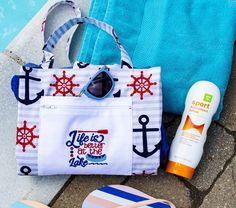 a beach bag, flip flops and sunscreen are sitting next to a towel