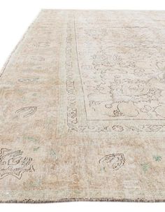 an antique rug with floral design on the bottom and green trimmings, in neutral tones